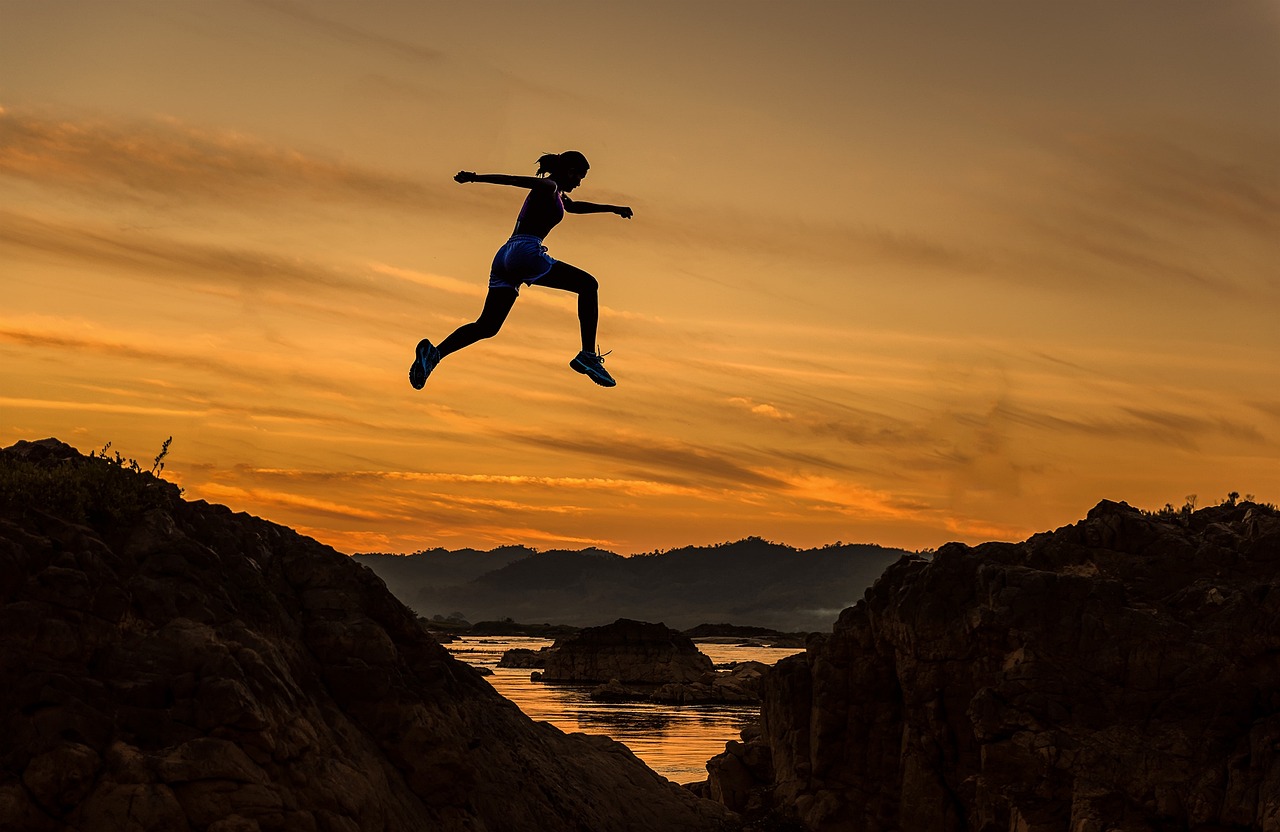 Nacht Sonnenuntergang Bild einer sportlichen jungen Frau springt über einen kleinen Fluss